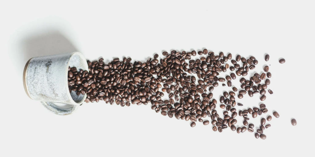 Coffee beans spilling out of a mug