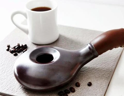 Coffee roaster sitting next to mug of coffee