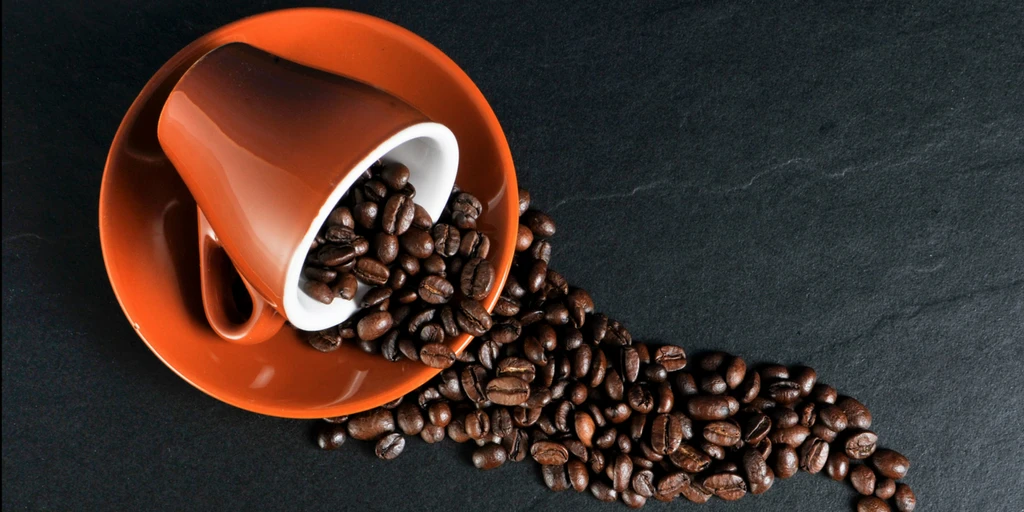 Coffee beans spilling out of espresso cup